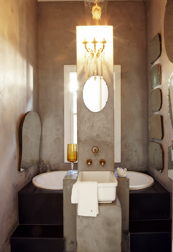 awesome concrete bathroom with many vintage mirrors