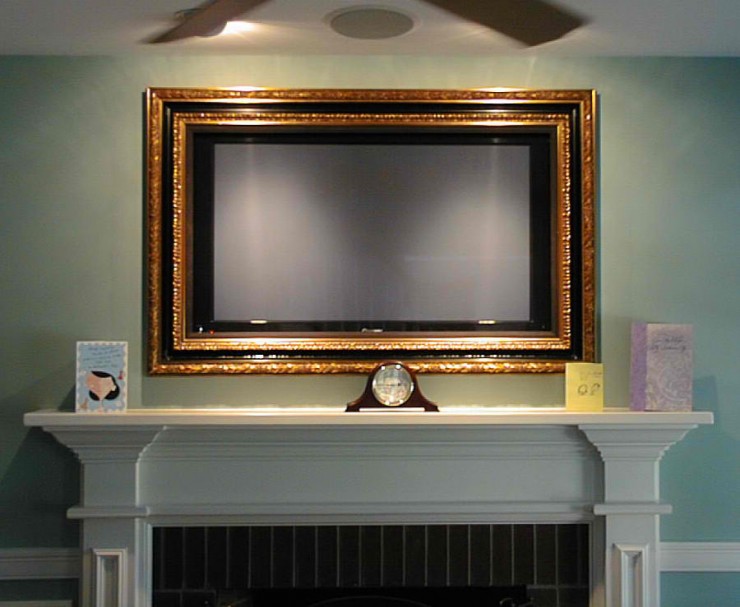 gold framed tv above fireplace