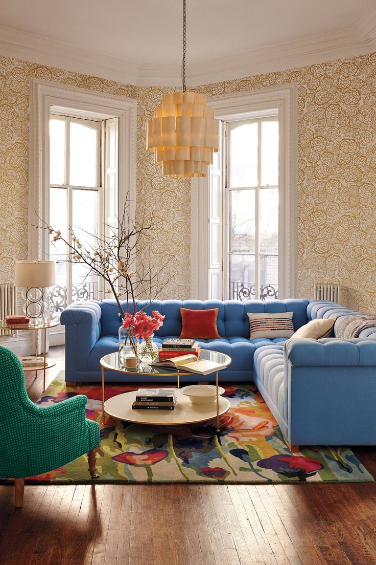 The sitting room of Eva Chen, Lucky’s editor in chiefliving room with blue corner sofa gold wallpaper and modern floral rug