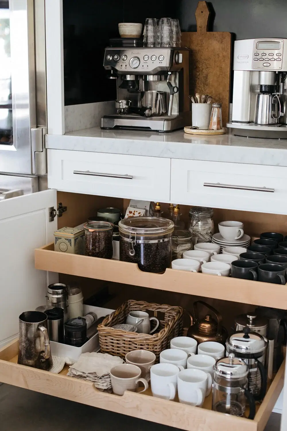 Organized coffee station drawers with mugs, coffee beans, tea, and brewing accessories