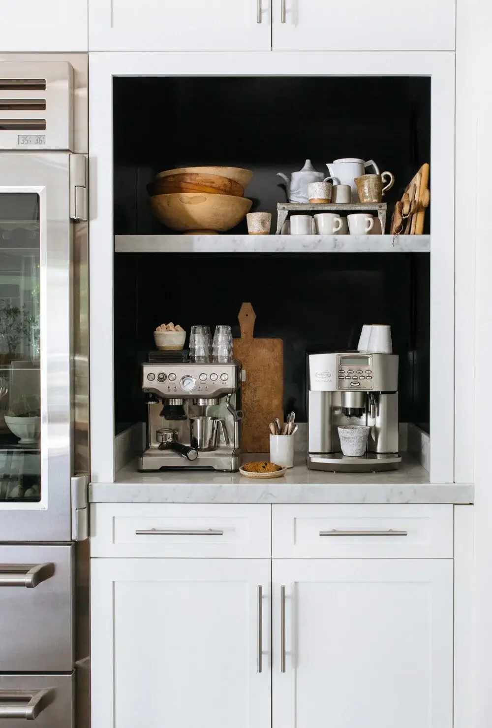 Built-in home coffee station with marble shelves, espresso machines, and styled open storage