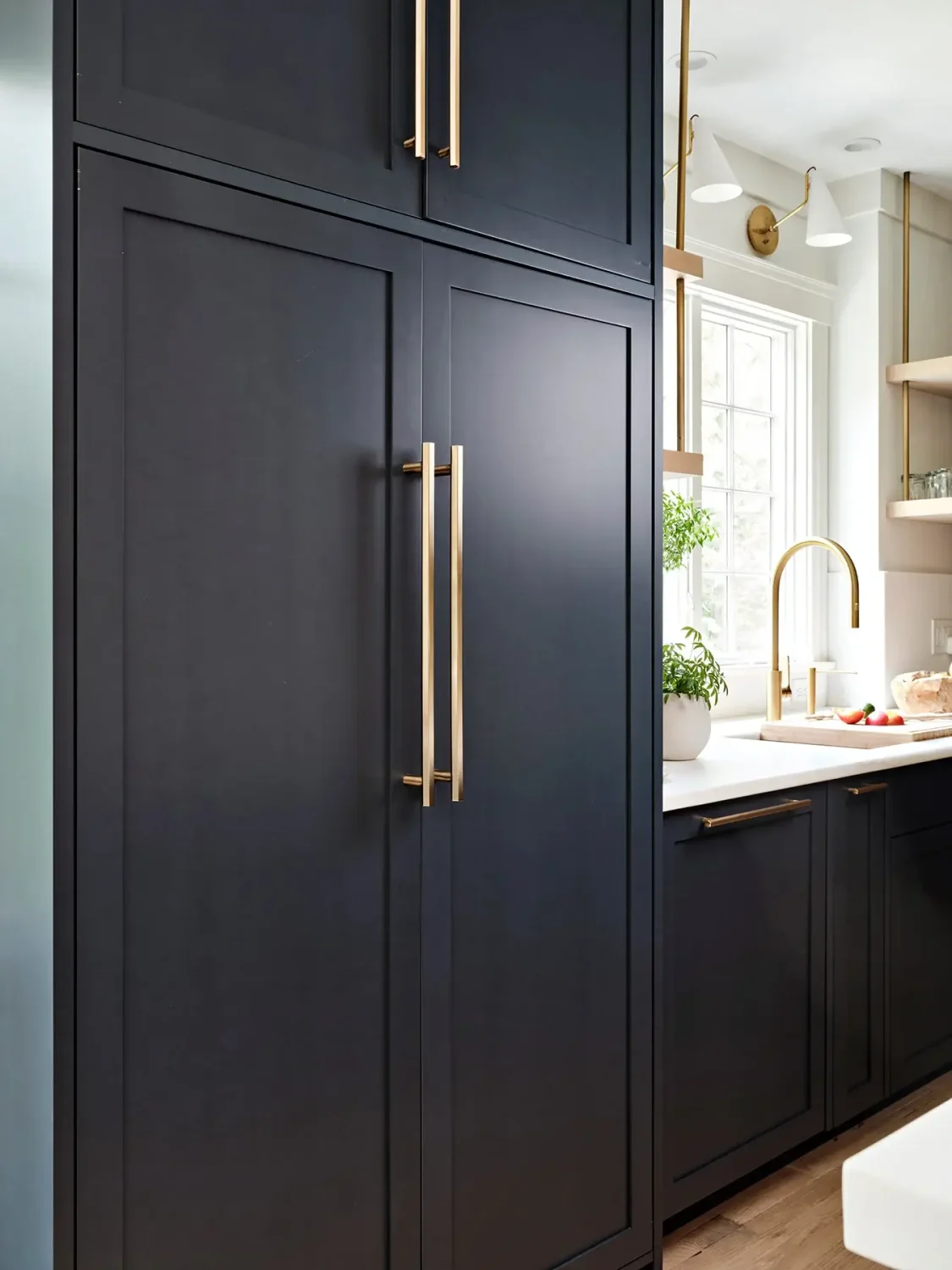 Tall navy kitchen cabinet with brass hardware concealing a hidden coffee bar