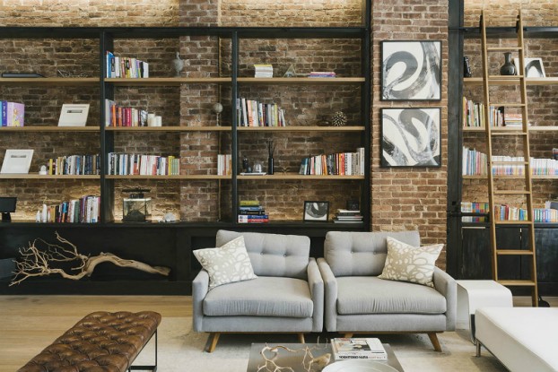 industrial living room with brick wall gray armchairs and black library