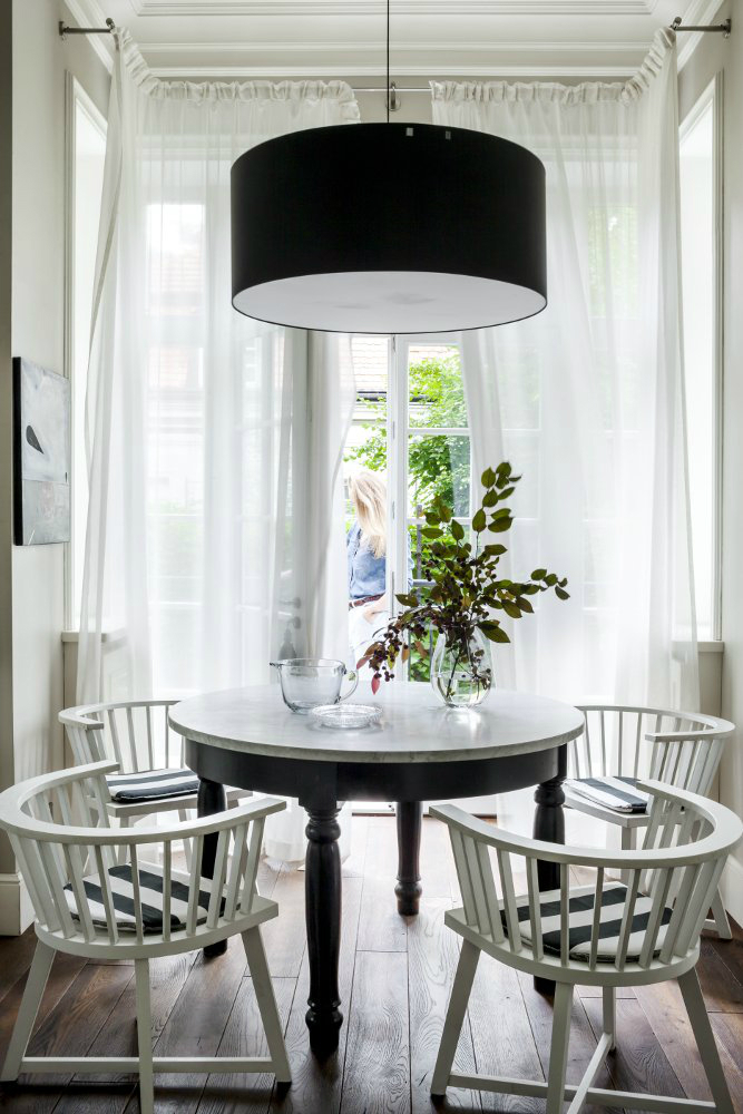 dining room with white chairs small black round table and black pendant