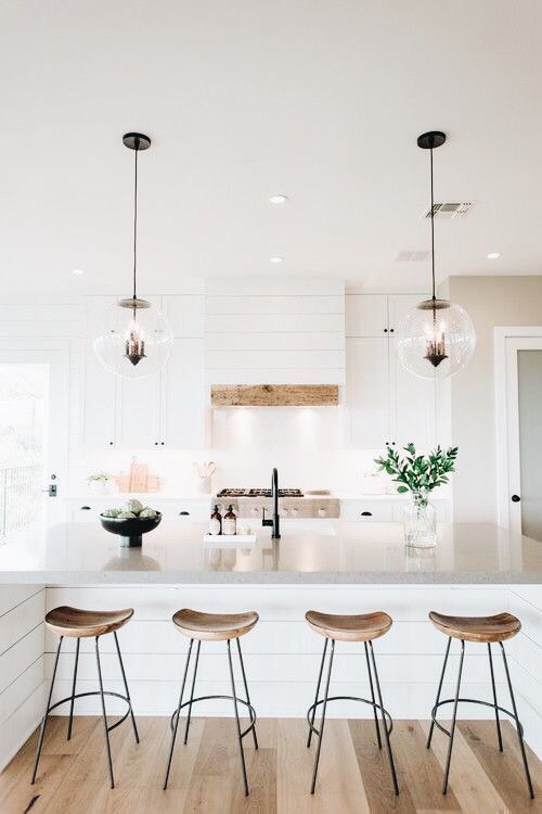 Open all-white kitchen with wooden stools