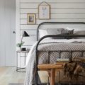 contemporary country white bedroom with black iron bed and wood flooring
