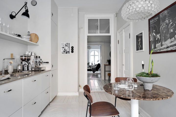 all white simple Scandinavian kitchen without upper cabinets with breakfast nook  with small round brown marble table
