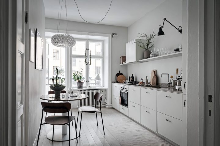 white simple Scandinavian kitchen without upper cabinets with breakfast nook