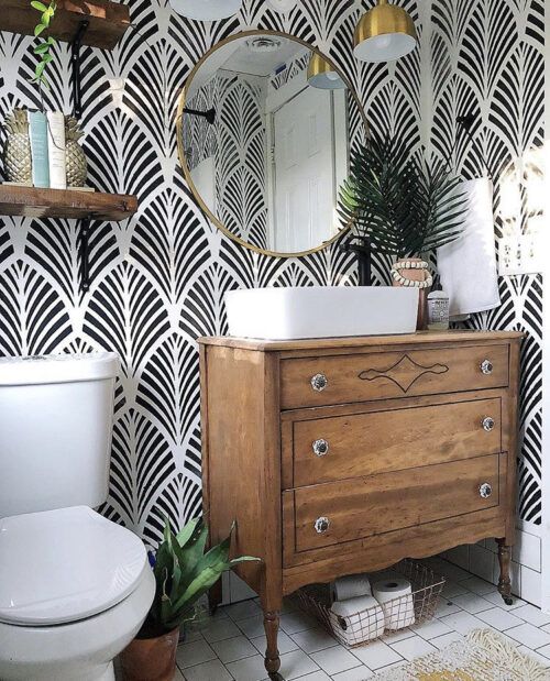 small bathroom with black and white wallpaper wood dresser vanity gold round mirror wood shelves and hanfing gold penant lights