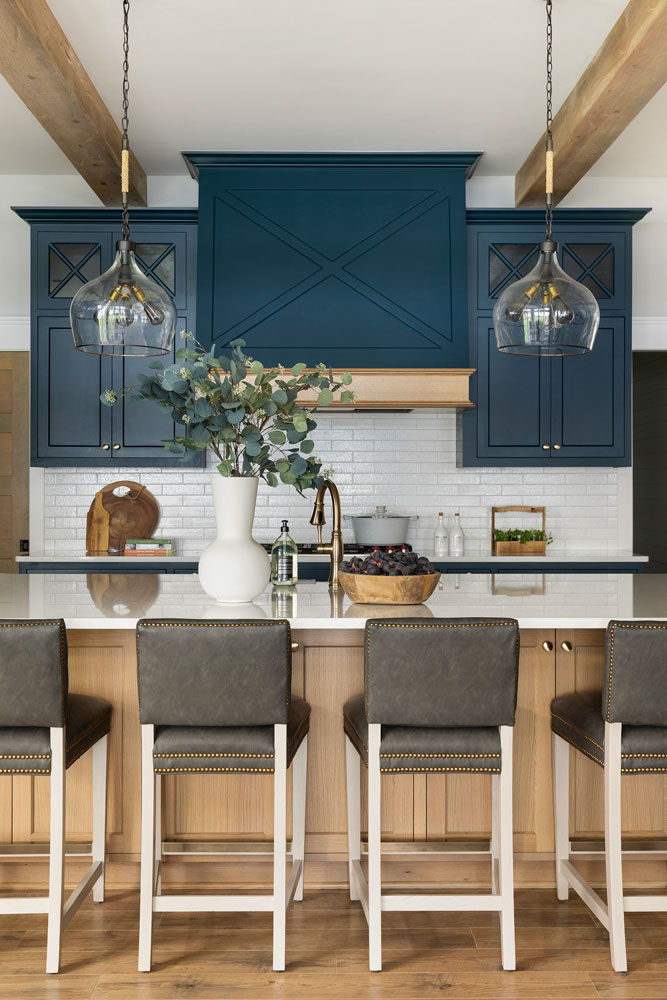 navy blue kitchen cabinets with light wood island and brown leather stools