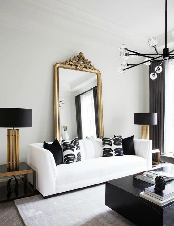 modern living room whith white sofa with black pillows black coffee table and gold french mirror