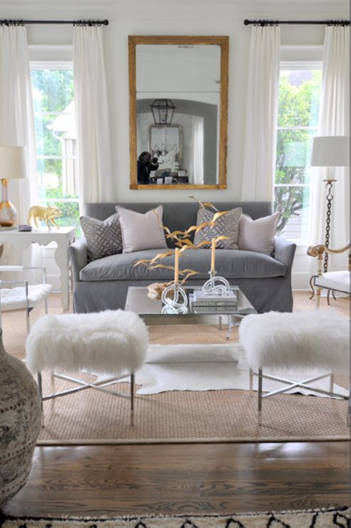 pastel living room with grey sofa white fur stools and gold leaf mirror