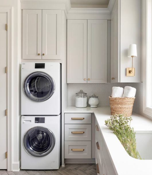 elegant laundry room with stacked washer and dryer gols handles and sink