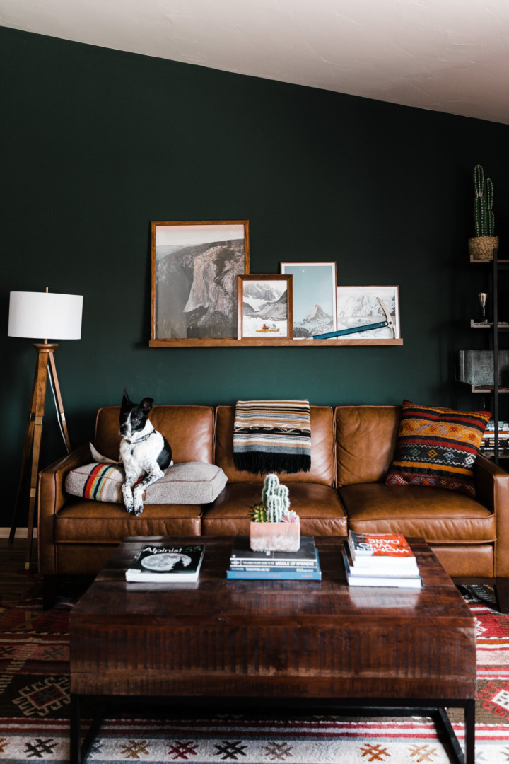dark greeen accent wall living room with brown leather sofa and decorative shelf