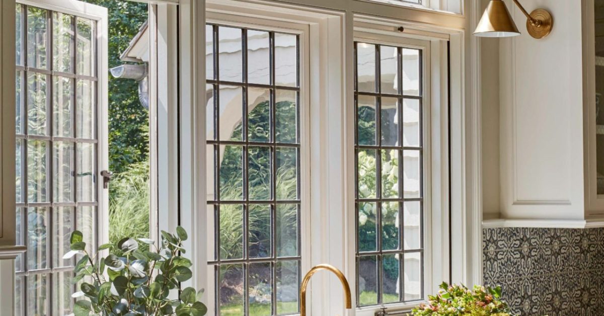 English cottage style kitchen with large windows and gold brass kitchen sconce lights