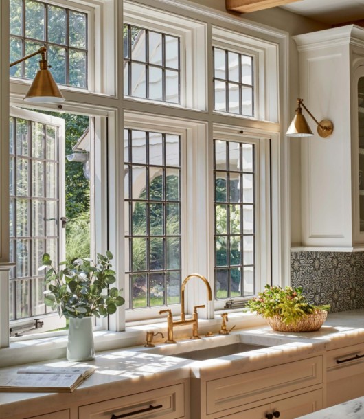 English cottage style kitchen with large windows and gold brass kitchen sconce lights