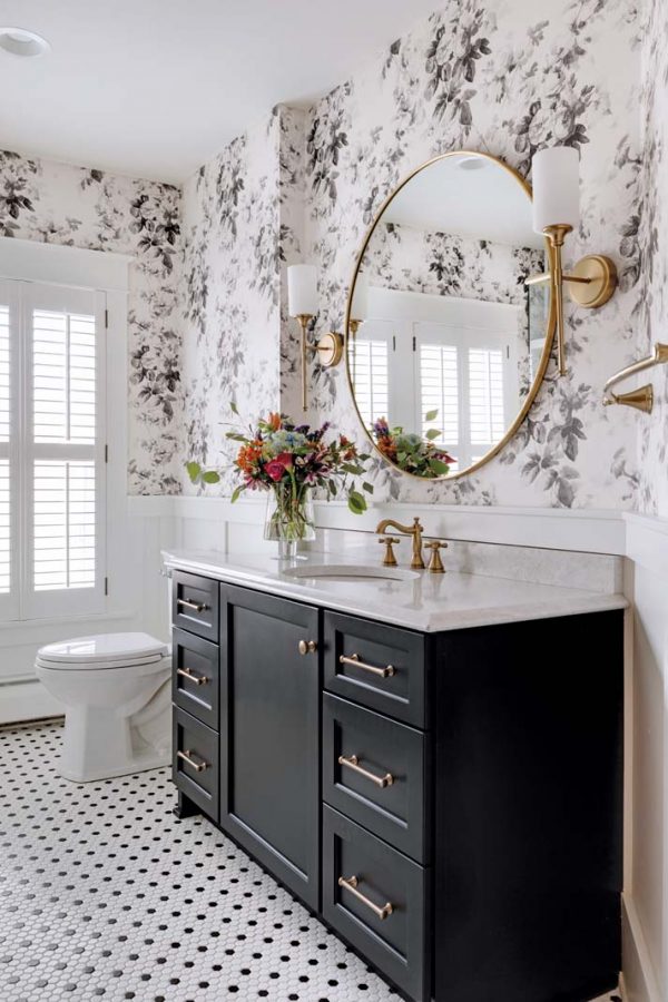 black and white bathroom with black-and-gray floral wallcovering and gold  hardware