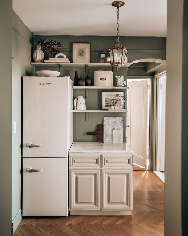 dark green wall painted kitchen  with old white painted cabinet and white floating shelves