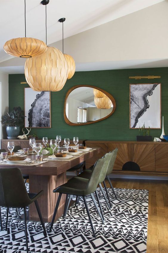 dining room with  irregular shaped  wood frame decorative mirror on the wall and green wall
 