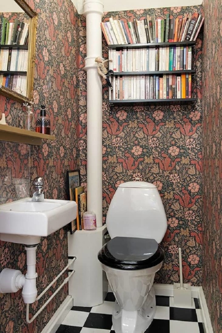 bathroom with books above the toilet