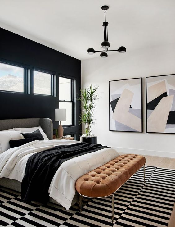 bedroom with black accent wall black and white striped bedroom aoranged brown suede tufted bench and two oversized abstract wall art