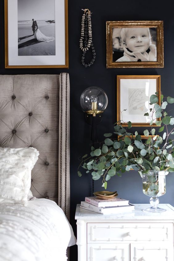 black and white bedroom with beige bed white nightstand and family photos on the wall