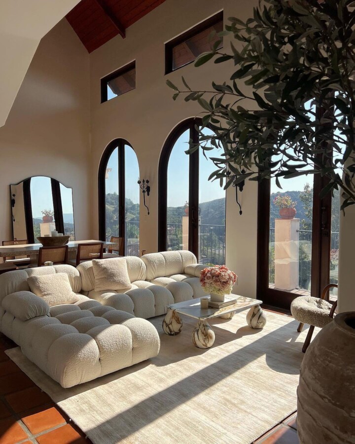 modern cream living room with teracotta tiles high windows cream boucle Camaleonda Sofa and unique calacatta monet marble coffee table