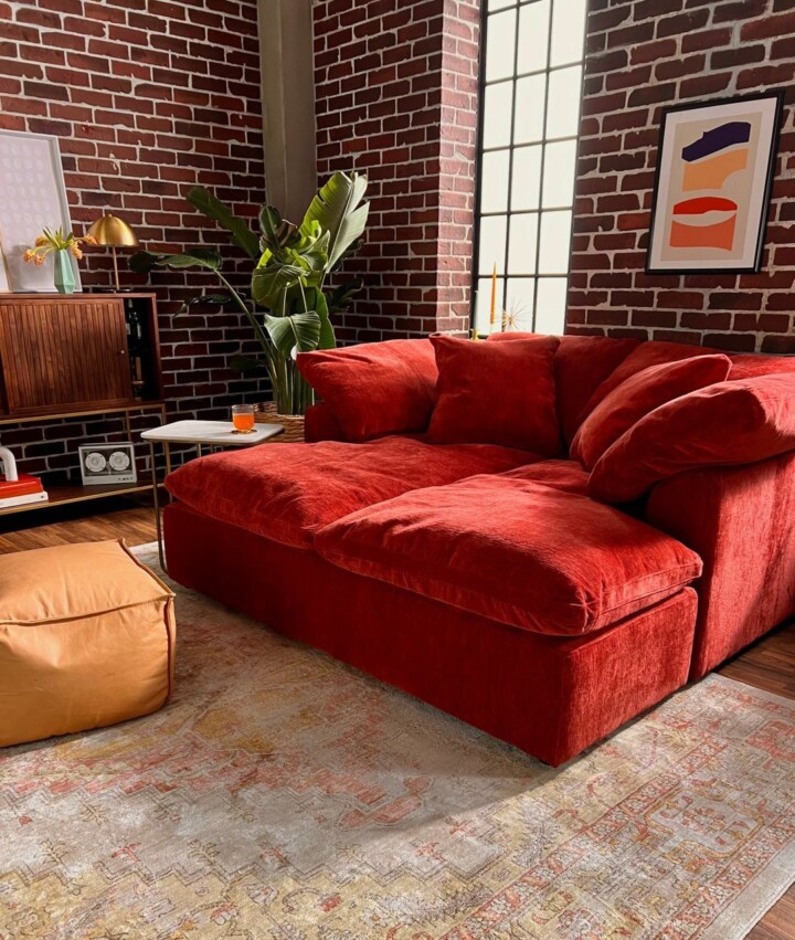 living woom with red brick walls and modern red velvet sofa