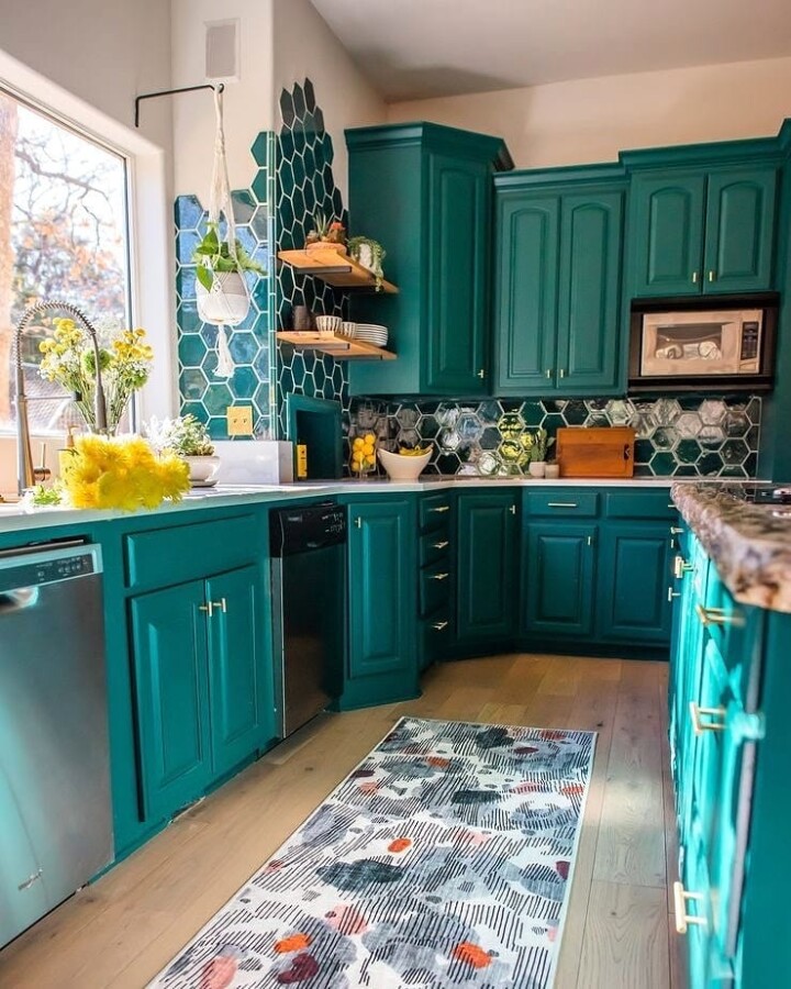 a bright kitchen with teal cabinets, mismatching tile backsplash, colorful  accessories…