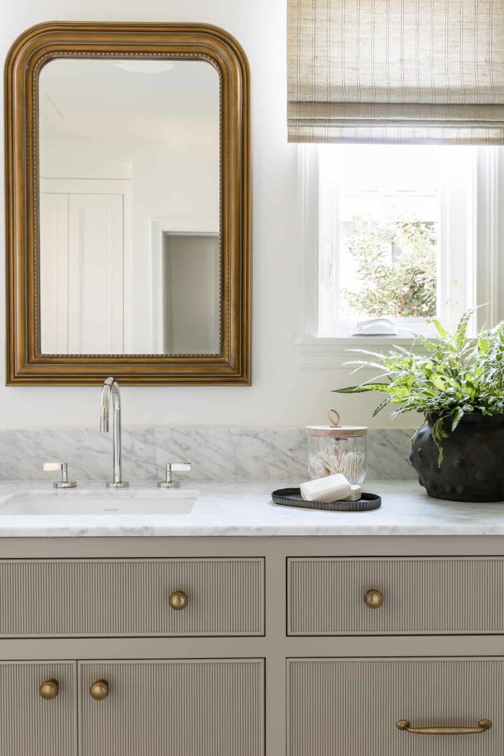 bathroom with polished nickel plumbing fixtures accented with burnished bronze cabinet hardware sconce, and vanity mirror