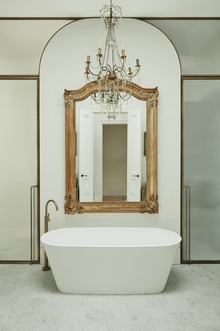 bathroom with free standing tub and large wood mirror by Hancock Architects
