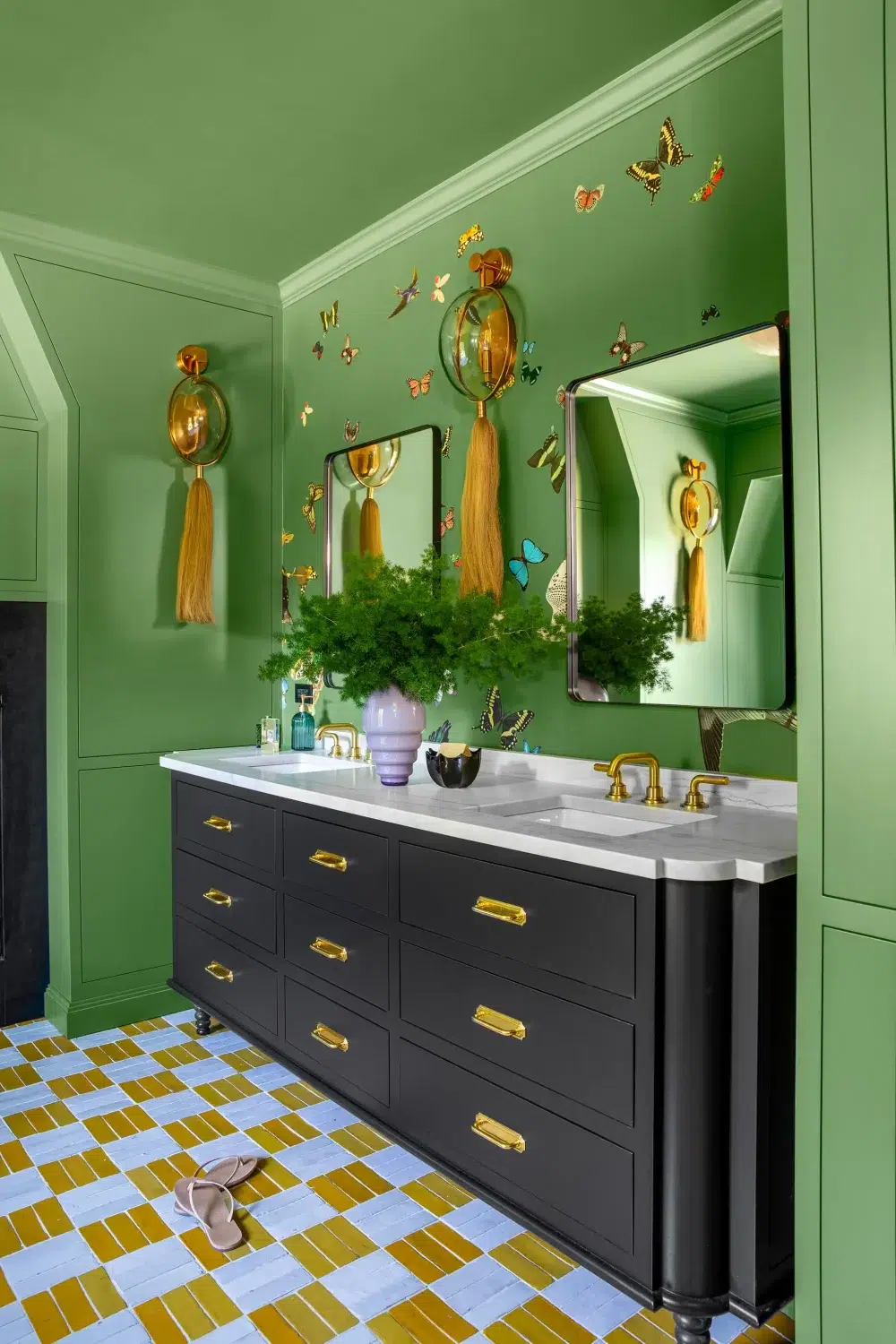 Vibrant green bathroom featuring brass fixtures, butterfly wall art, black vanity, and eclectic vintage-inspired design by North & Madison.
