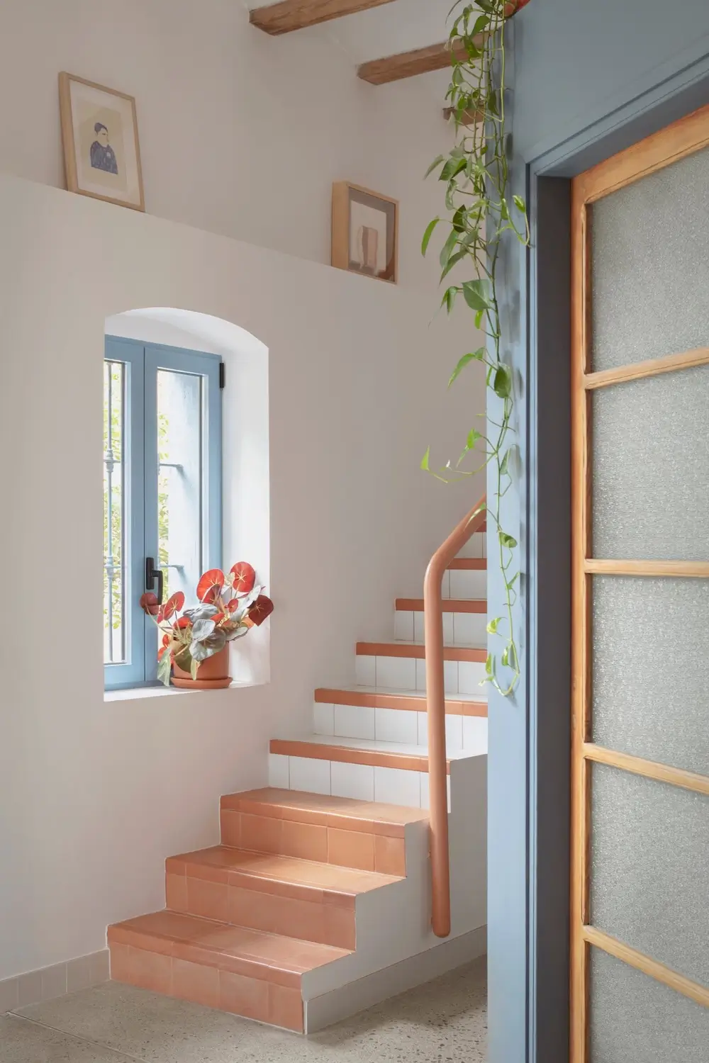 Close-up of terracotta-tiled stairs and blue window frame in Casa Patio, Valencia