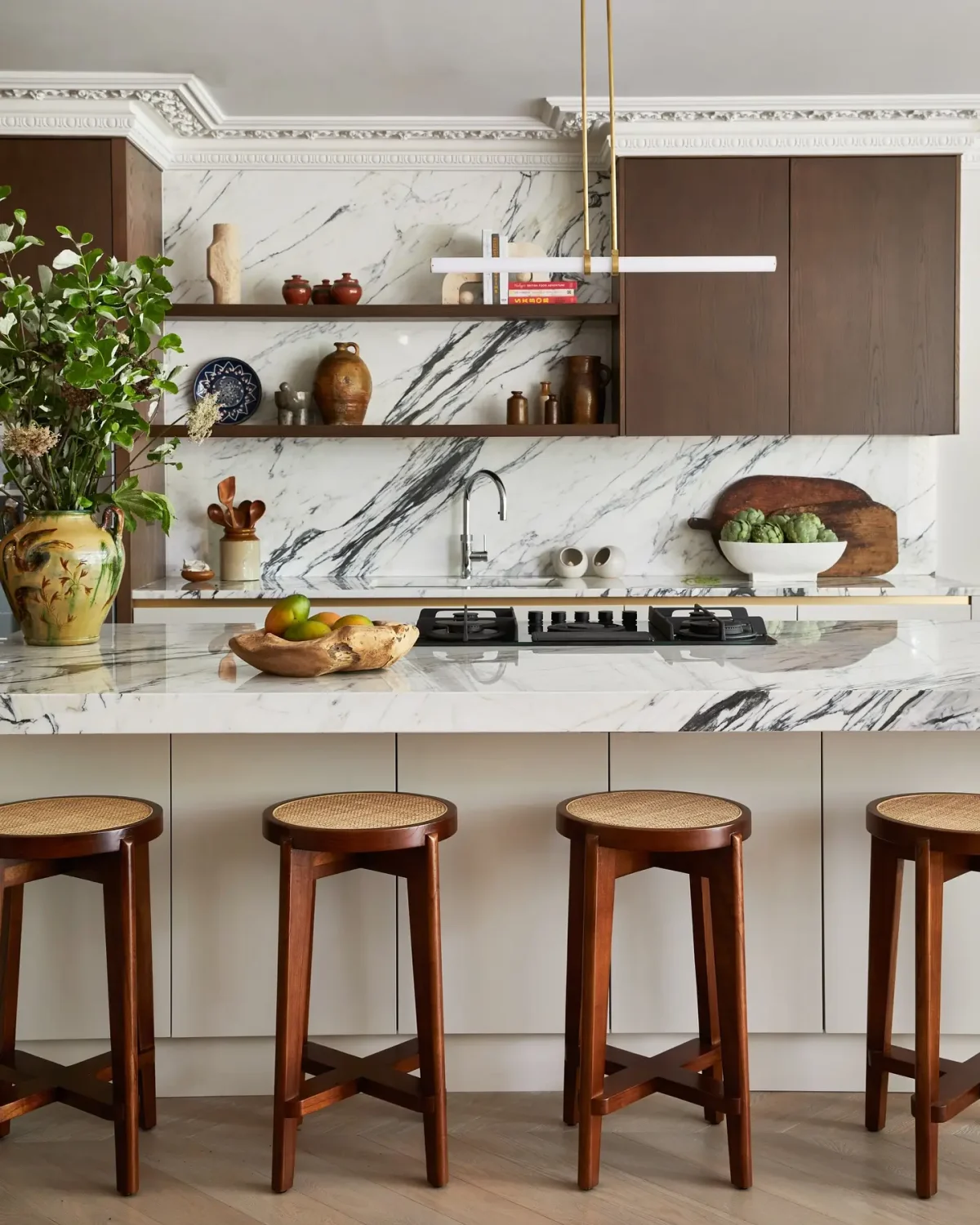High-end kitchen with marble surfaces and designer wood stools with cane detailing