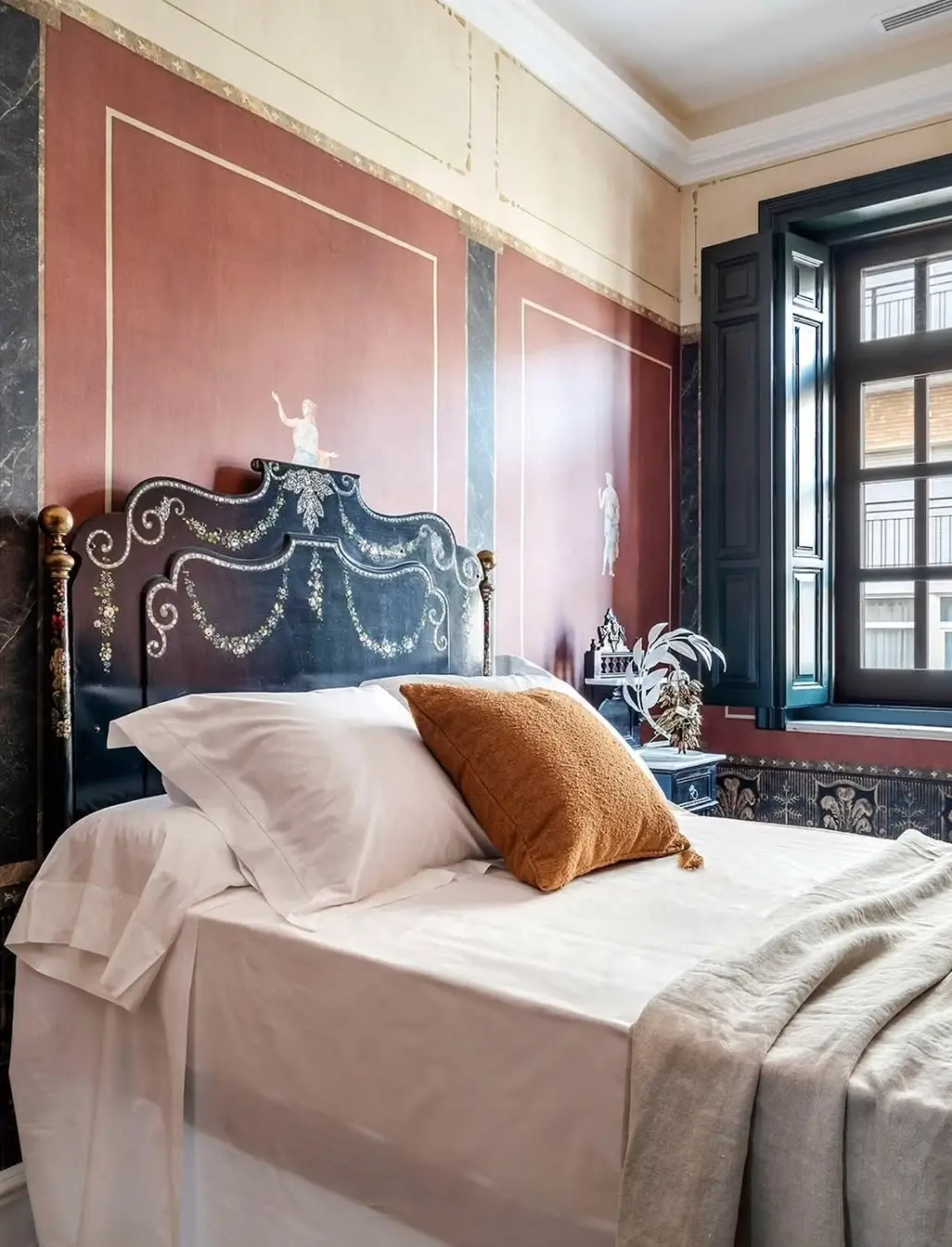 Elegant bedroom view in a restored Murcia mansion with patterned tile flooring, a sculptural lounge chair, classic moldings, and a doorway framing a bright room with a chandelier and sea views.