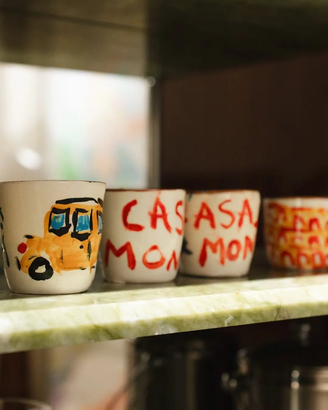 Hand-painted ceramic cups created by artist Michael McGregor displayed on a marble shelf inside Casa Monti Rome.