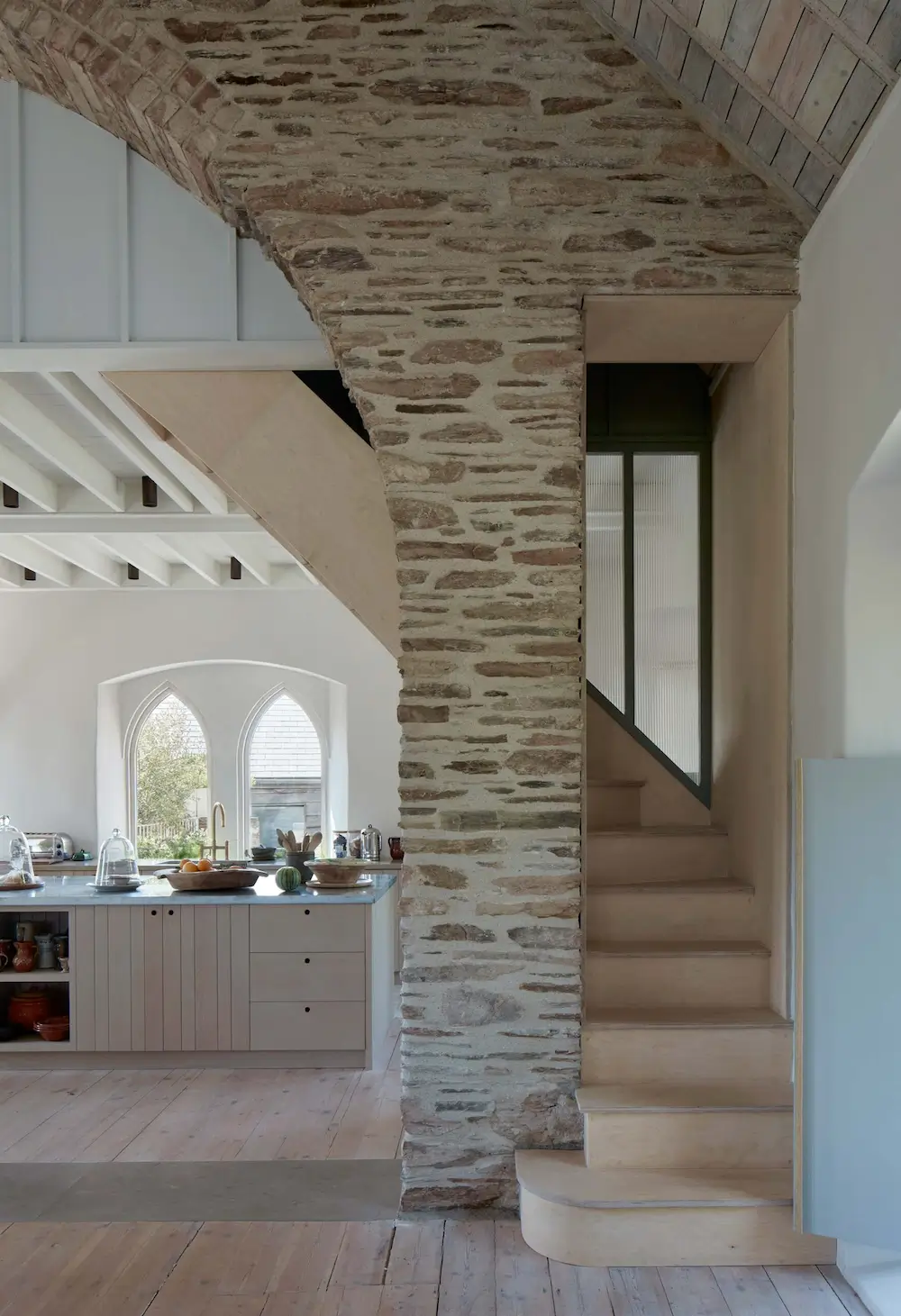 Stone archway and plywood staircase inside The Old Chapel renovation by Tuckey Design Studio.