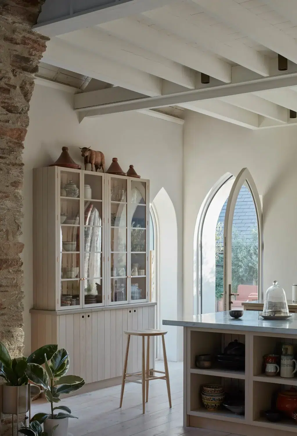 Pale timber kitchen cabinetry and arched glass doors inside a converted chapel home.