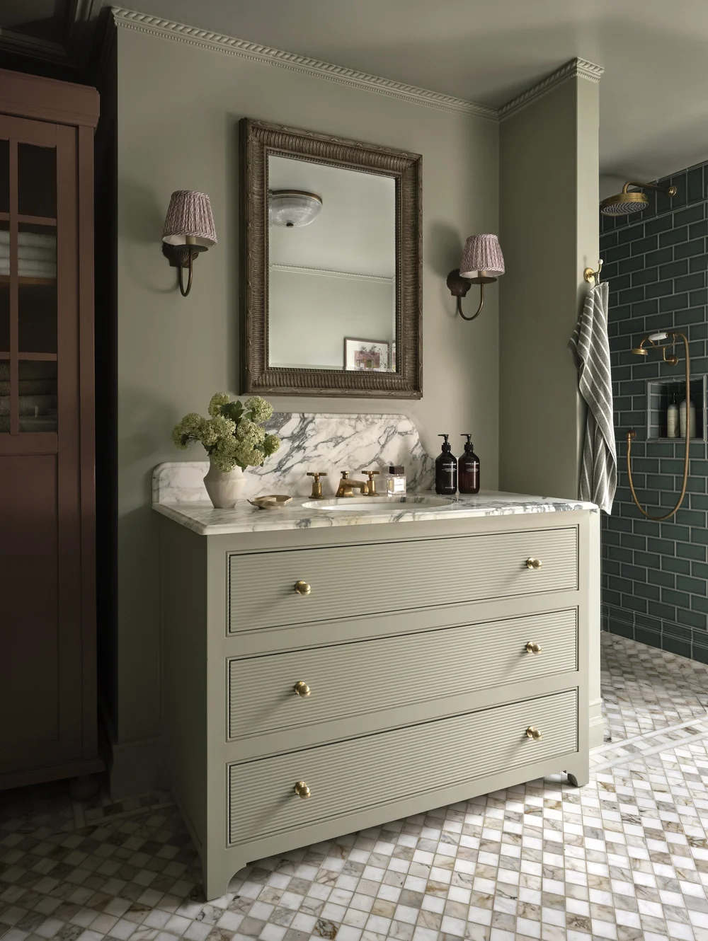 Traditional bathroom by Frank and Faber featuring a sage green fluted vanity with a marble countertop, brass fixtures, an antique-style mirror, and a walk-in shower with deep green subway tiles.