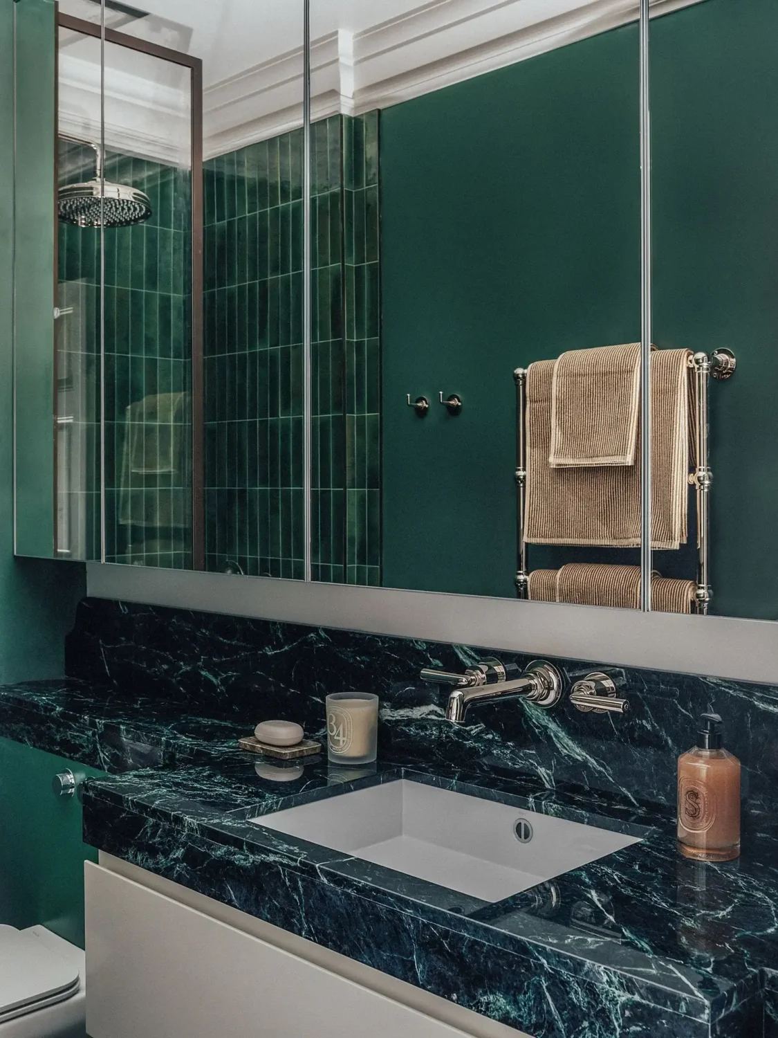 Luxury green marble bathroom with emerald walls, mirrored cabinets, and chrome fixtures in a Mayfair apartment.