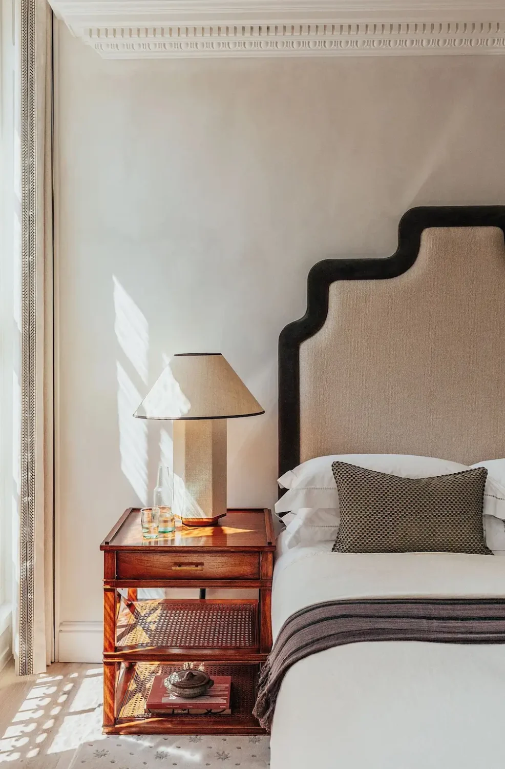 Luxury bedroom with sculptural upholstered headboard, walnut bedside table, and contemporary table lamp.
