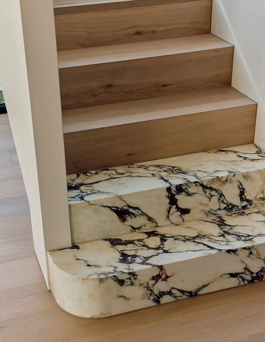 Custom staircase at the Ormond Residence by Alesi featuring warm Dune oak flooring paired with Calacatta Viola marble steps with striking burgundy veining.