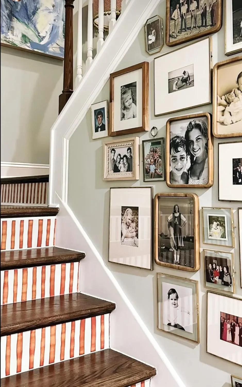 Striped staircase risers beneath a family gallery wall, featuring warm terracotta-and-white stripes that add personality to a traditional hallway.