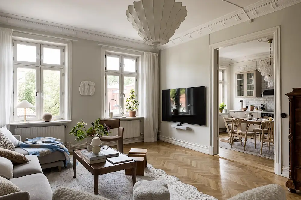Light-filled Scandinavian living room with herringbone floors and a view into the kitchen.