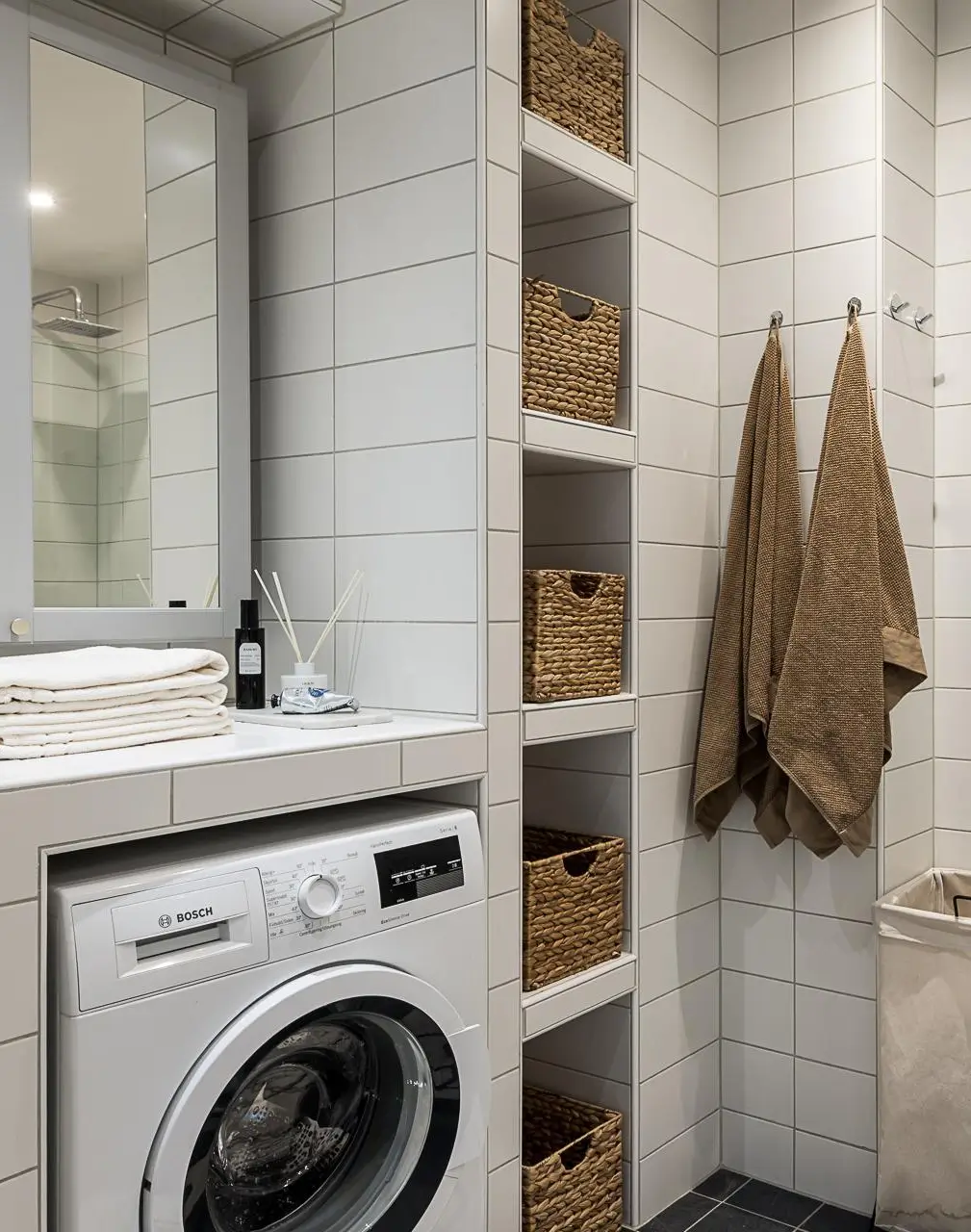 Scandinavian bathroom with white tiles, built-in storage, and integrated laundry area.
