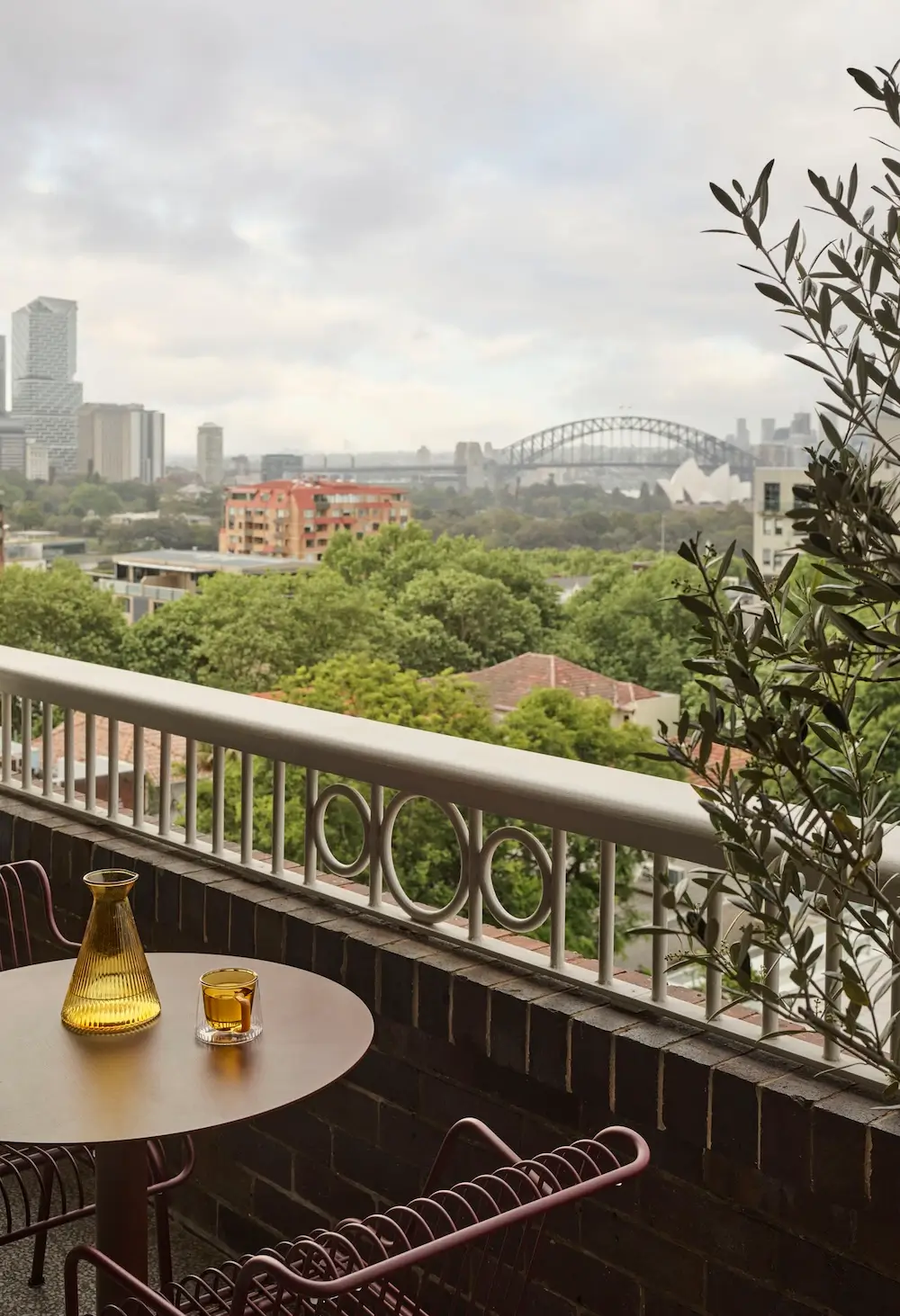 Balcony at The Gentleman apartment by YSG Studio overlooking Sydney Harbour with views of the Sydney Harbour Bridge and Sydney Opera House.