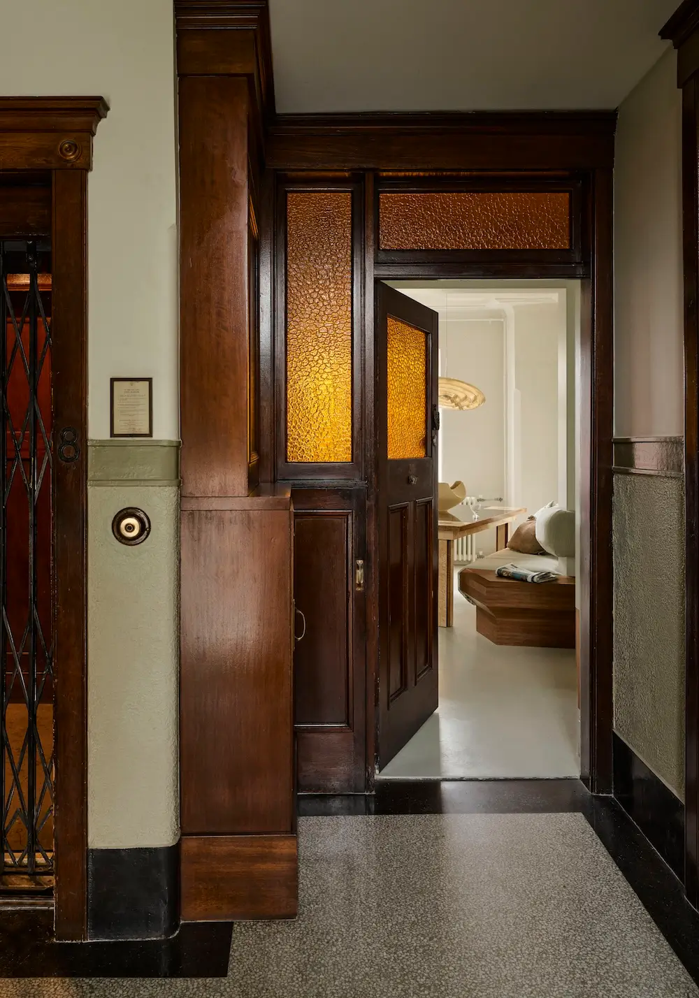 Original Art Deco entryway in The Gentleman apartment by YSG Studio featuring dark timber joinery, amber Flemish glass panels, and restored heritage detailing.