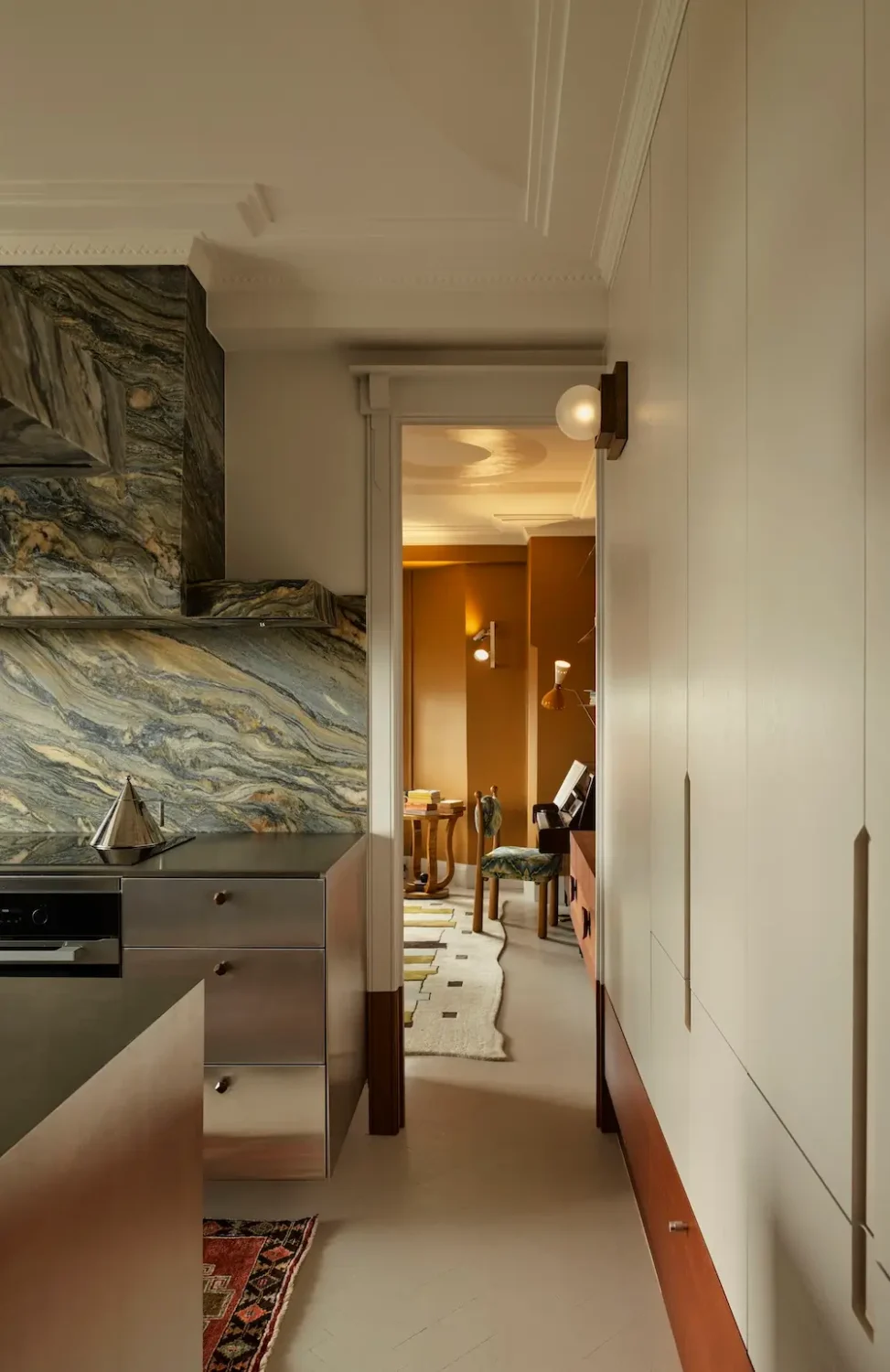 Kitchen corridor in The Gentleman apartment by YSG Studio featuring Lauriana quartzite, polished aluminium cabinetry, and minimalist custom storage.
