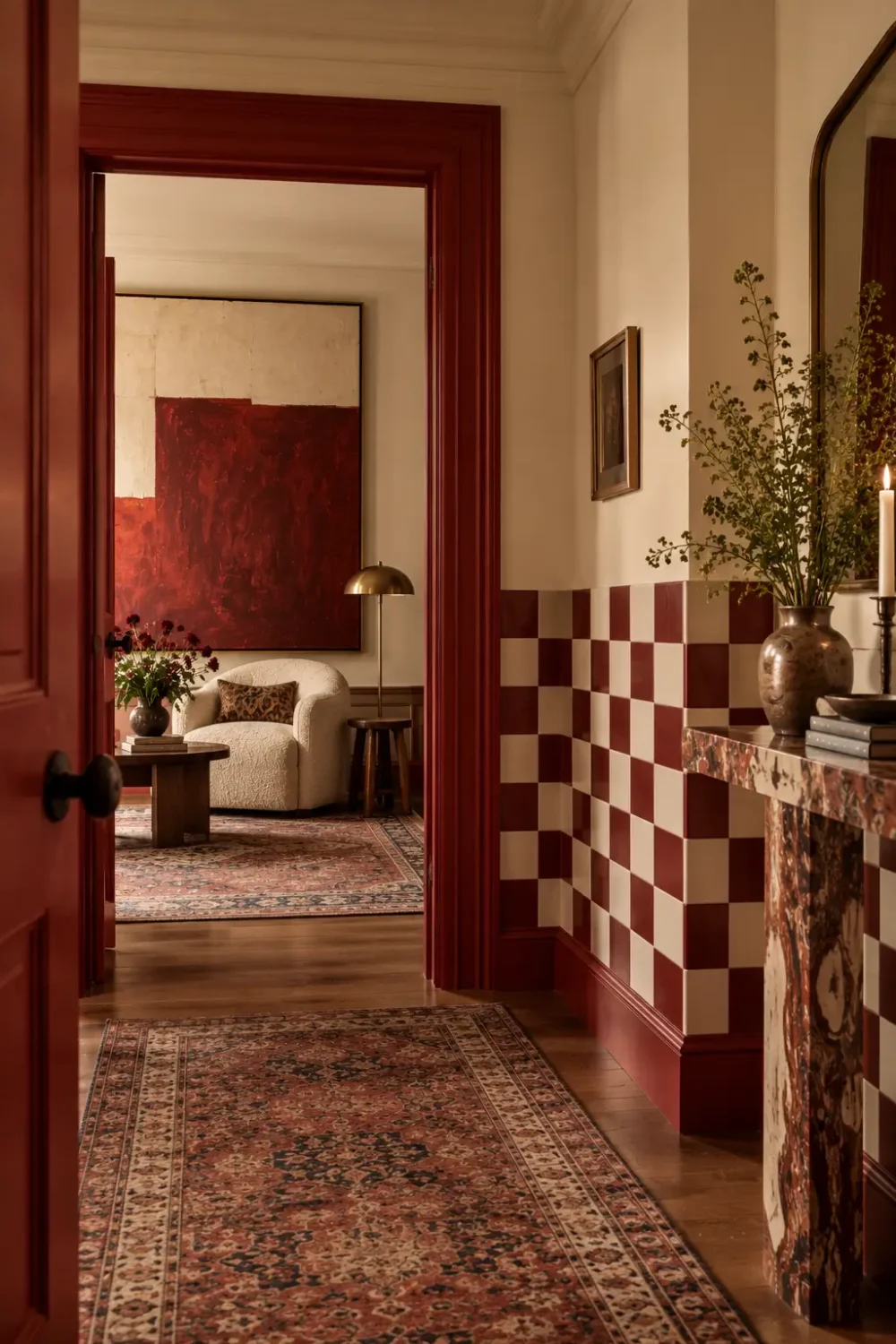 Eclectic hallway with checkerboard walls, a deep red painted doorframe and oversized artwork, showing how unexpected design choices add personality.